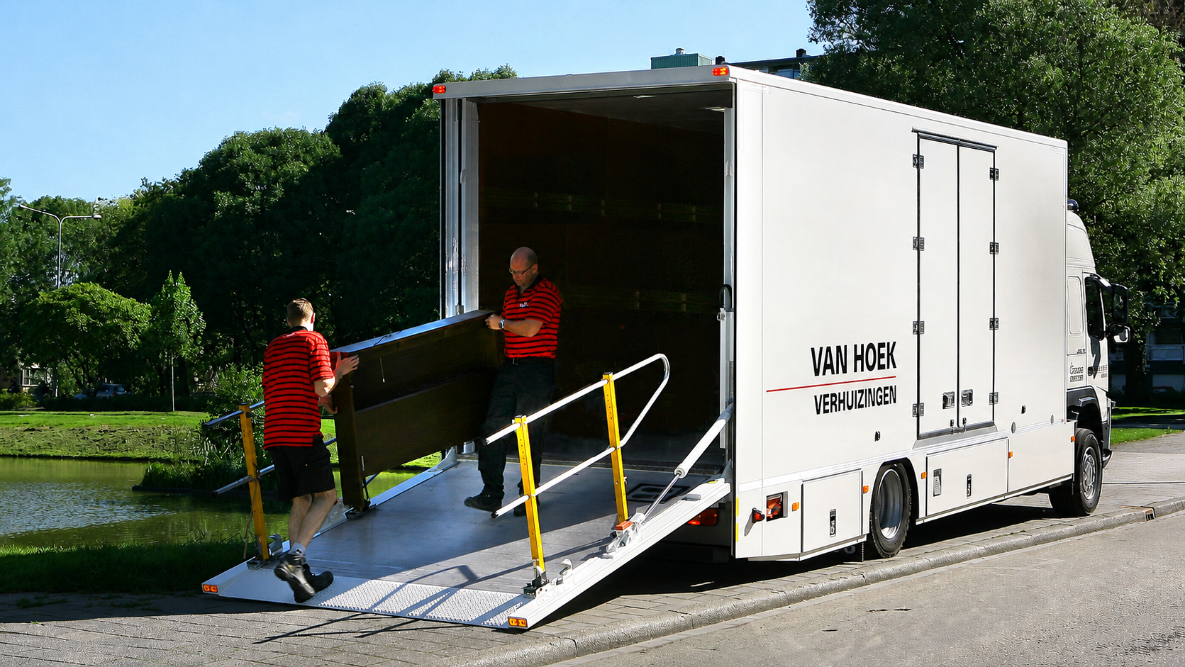 Verhuizing Twee werknemers van Van Hoek Verhuizingen dragen een meubelstuk uit een witte vrachtwagen met de tekst Van Hoek Verhuizingen erop.